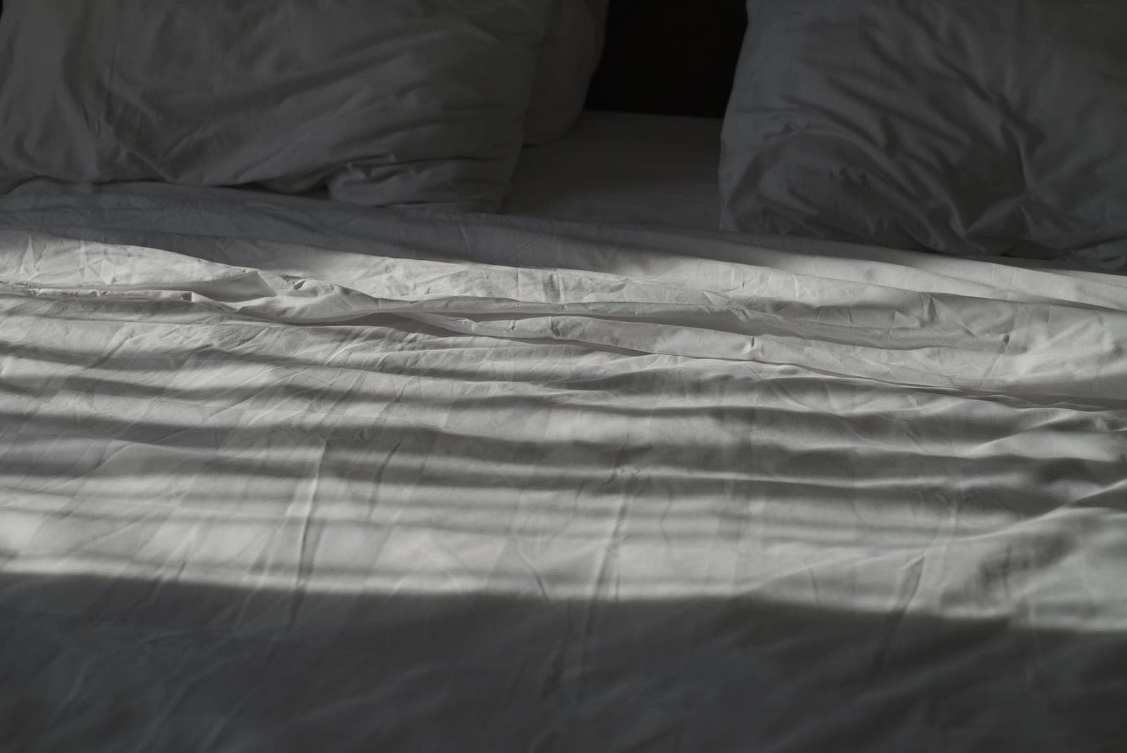 Quiet bedroom at dawn with linen bedding and low warm light
